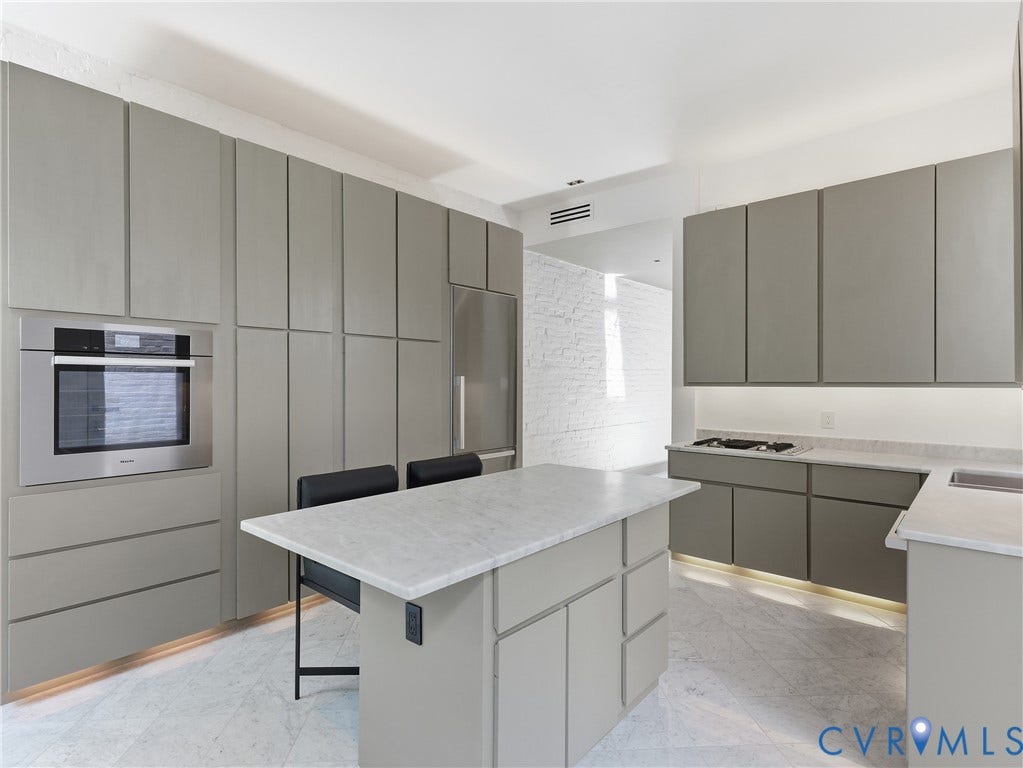 Sleek kitchen featuring integrated cabinetry, built-in stainless steel appliances, a center island with countertop, and under-cabinet lighting