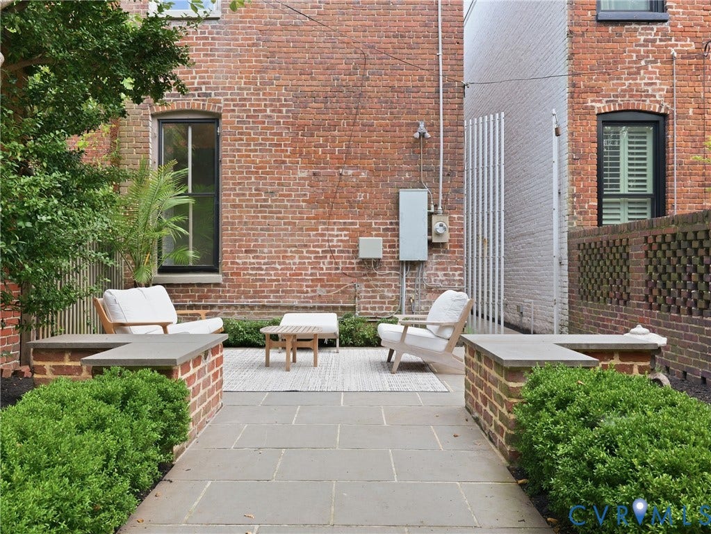 Brick exterior with black-framed windows, a stone patio, and a brick privacy wall