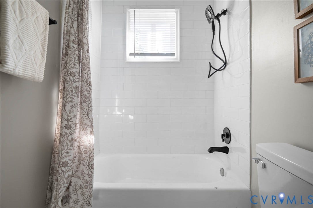 5429 Parker Street, Fulton Hill, Richmond, VA 23231 Bathtub with white subway tile surround, matte black shower fixtures, and a window with blinds