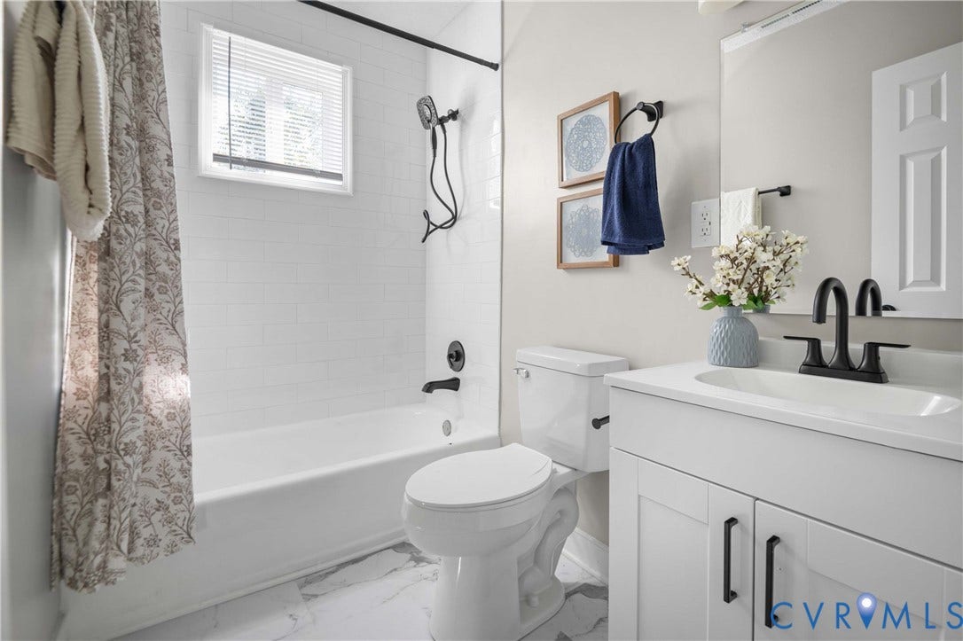 5429 Parker Street, Fulton Hill, Richmond, VA 23231 White subway tile shower surround, white vanity with integrated sink, black plumbing fixtures, white-finish flooring, and a white toilet