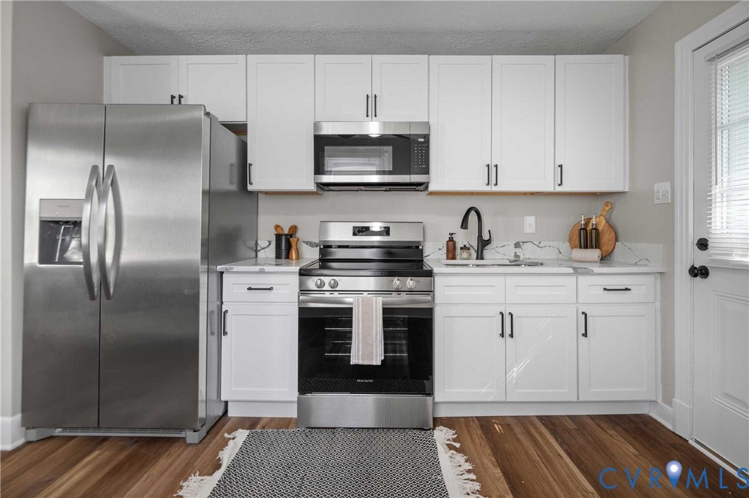 5429 Parker Street, Fulton Hill, Richmond, VA 23231 White cabinetry with matte black hardware, stainless steel appliances, wood-finish flooring, white countertop, and a black gooseneck faucet