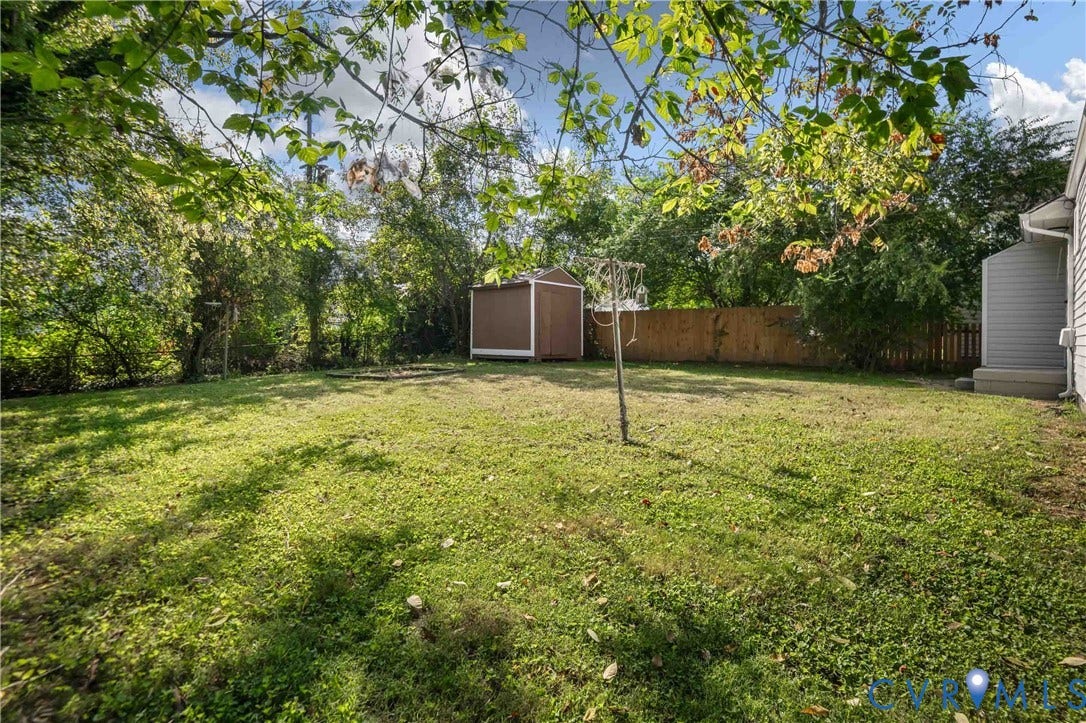 5429 Parker Street, Fulton Hill, Richmond, VA 23231 Expansive grass lawn with mature perimeter trees, a wood-finish storage shed, and a privacy fence