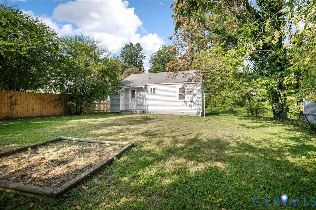 5429 Parker Street, Fulton Hill, Richmond, VA 23231 Expansive grassy yard with a wooden privacy fence, mature trees, and a raised garden bed