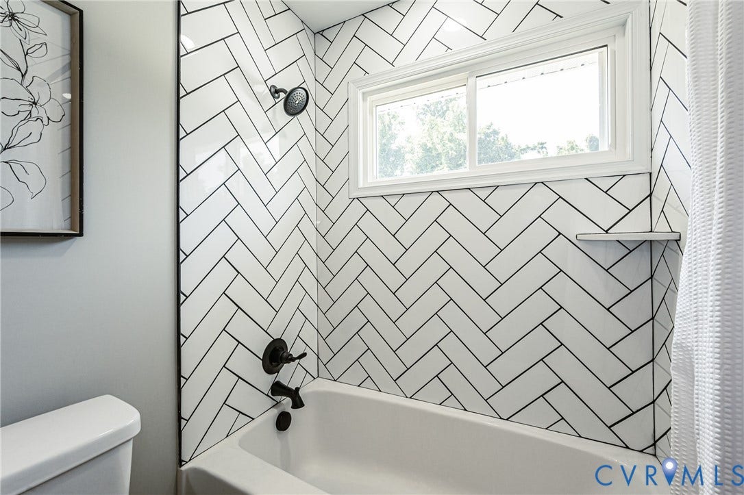 2702 Manchester Drive, New Birchett Estates, Prince George, VA 23875 Bathtub with herringbone tile surround, black plumbing fixtures, and integrated shower shelf