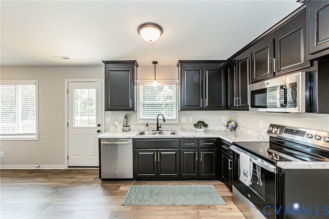 2702 Manchester Drive, New Birchett Estates, Prince George, VA 23875 Kitchen featuring dark wood-finish cabinetry, stainless steel appliances, light-toned countertops, and wood-finish flooring