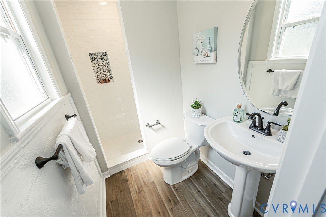 2702 Manchester Drive, New Birchett Estates, Prince George, VA 23875 Pedestal sink with dark-toned fixtures, wood-finish flooring, and a tiled shower with an accent niche