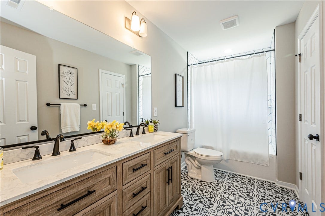 2702 Manchester Drive, New Birchett Estates, Prince George, VA 23875 Double vanity with wood-finish cabinetry, black hardware, and an expansive mirror