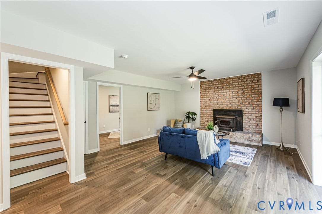 2702 Manchester Drive, New Birchett Estates, Prince George, VA 23875 Expansive living area featuring wood-finish flooring, a brick accent wall, and a ceiling fan