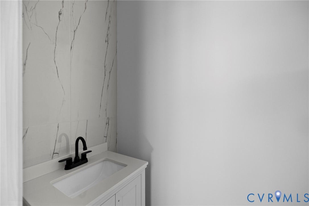 821 Fort Lee Road, North Dinwiddie, VA 23803 White vanity with an integrated sink, matte black faucet, and a large format tiled accent wall