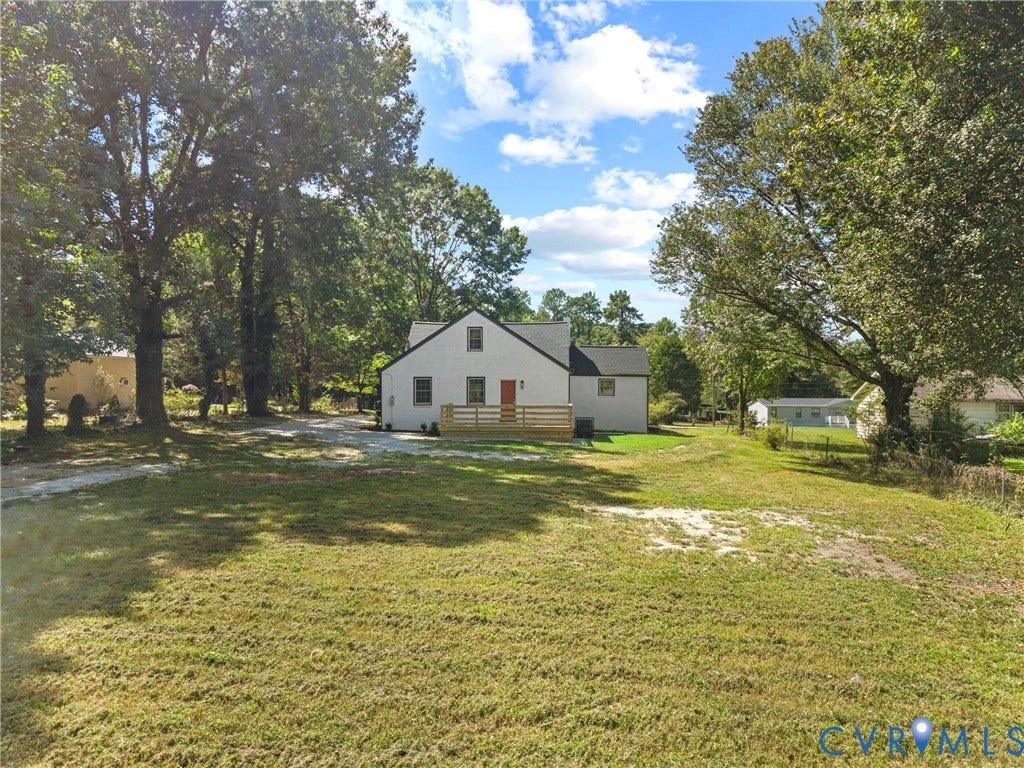 821 Fort Lee Road, North Dinwiddie, VA 23803 White exterior with a gable roof, accented by a red door and a wood-slat deck