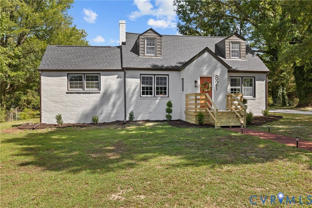 821 Fort Lee Road, North Dinwiddie, VA 23803 White brick exterior with dark trim windows, front porch with wooden railings, dark shingled roof, and dormer windows