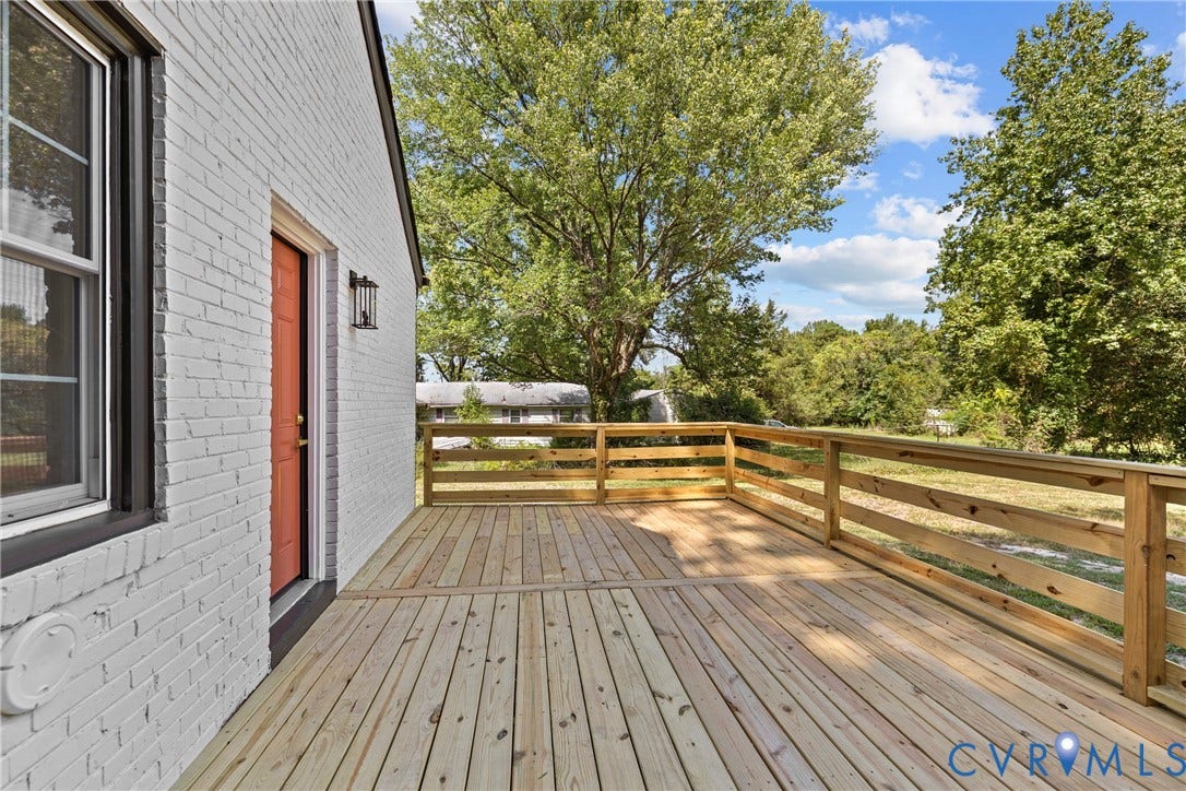 821 Fort Lee Road, North Dinwiddie, VA 23803 Expansive wood deck with a natural wood railing, white brick exterior, and a vibrant orange entry door