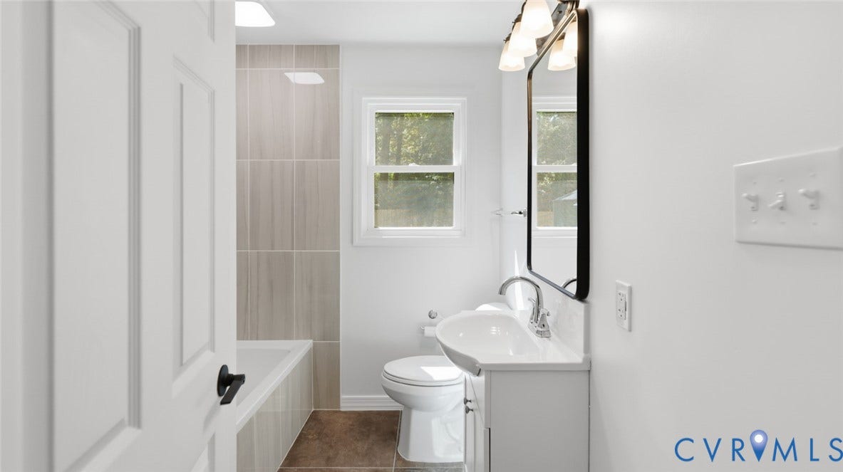 White vanity with an integrated sink, framed mirror, and a three-light sconce