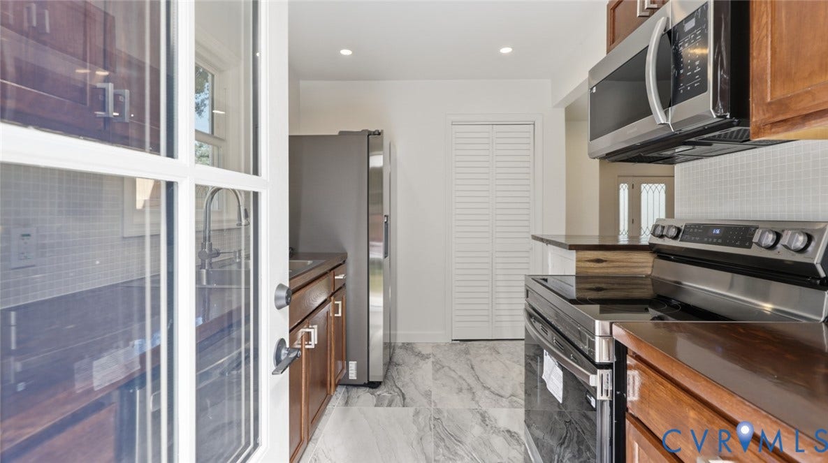 Wood-finish cabinetry with silver hardware, stainless steel appliances, white subway tile backsplash, recessed lighting, and marble-look flooring