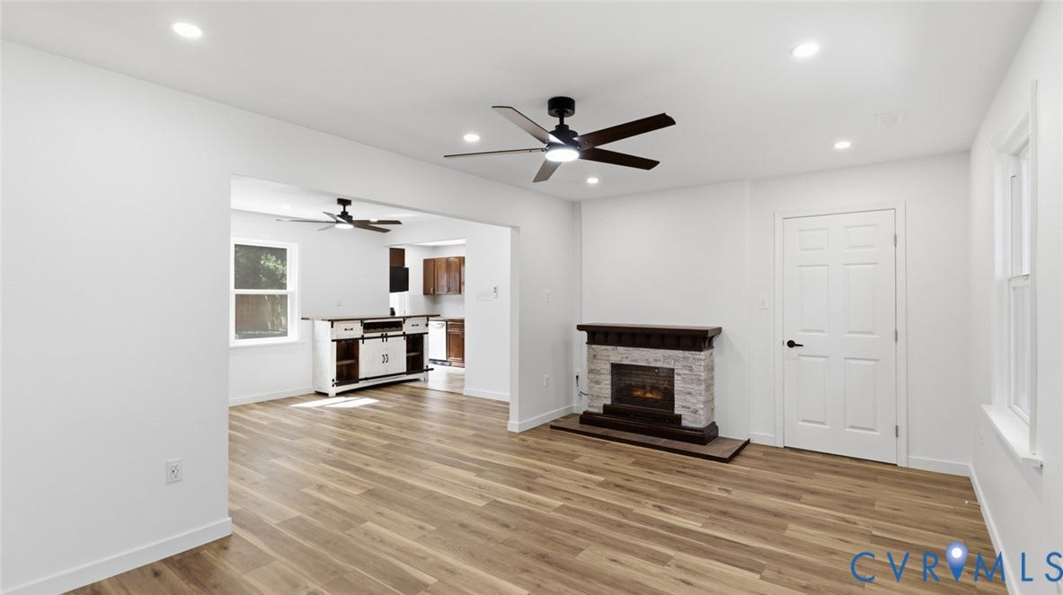 Wood-finish flooring throughout, featuring a fireplace with stone surround and dark wood mantel