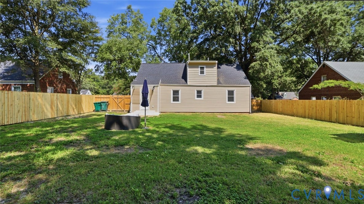 Expansive backyard featuring a manicured lawn, new privacy fencing, and a concrete patio