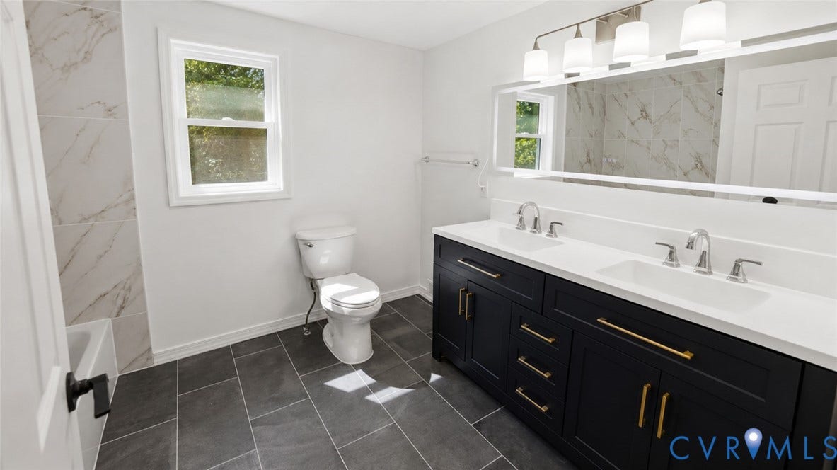 Dual sink vanity with quartz countertop, dark cabinetry, and gold-finish hardware