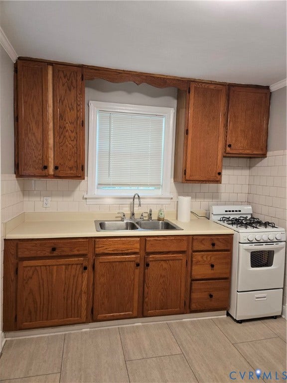 3427 W Franklin Street, Museum District, Richmond, VA 23221 Wood-finish cabinetry with black hardware, double basin stainless steel sink with gooseneck faucet, light-toned countertop, white subway tile backsplash, and tile flooring