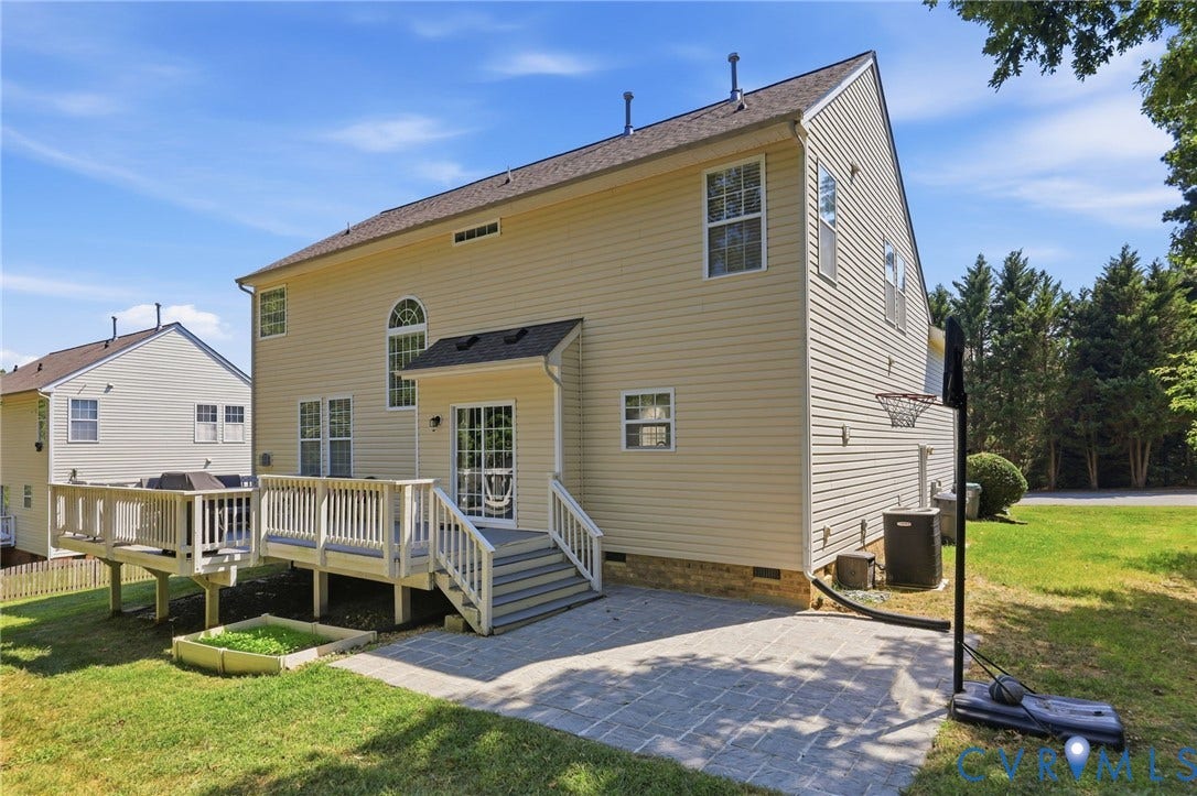 Expansive rear exterior featuring a multi-level wood deck, a paved patio, and a raised garden bed