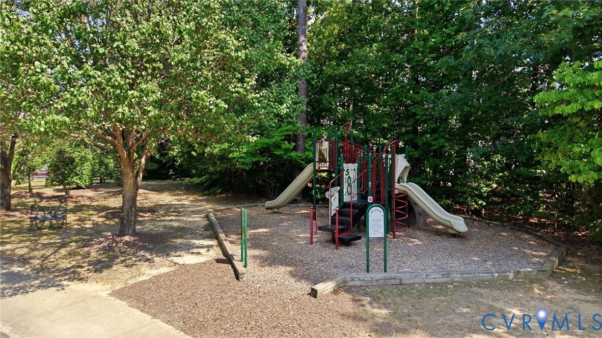 Recreational area featuring a playground structure with multiple slides, spring riders, and a climbing element