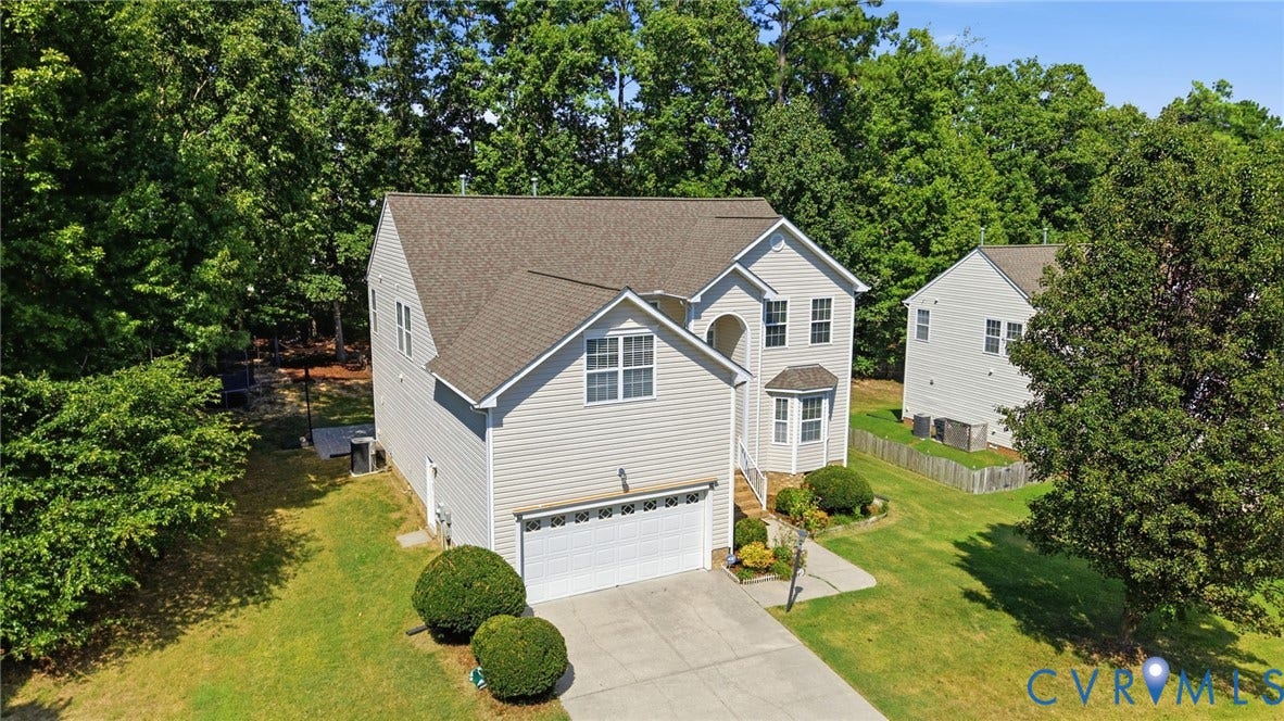 Two-story residence featuring light-colored siding, an attached garage, a bay window, and a concrete driveway