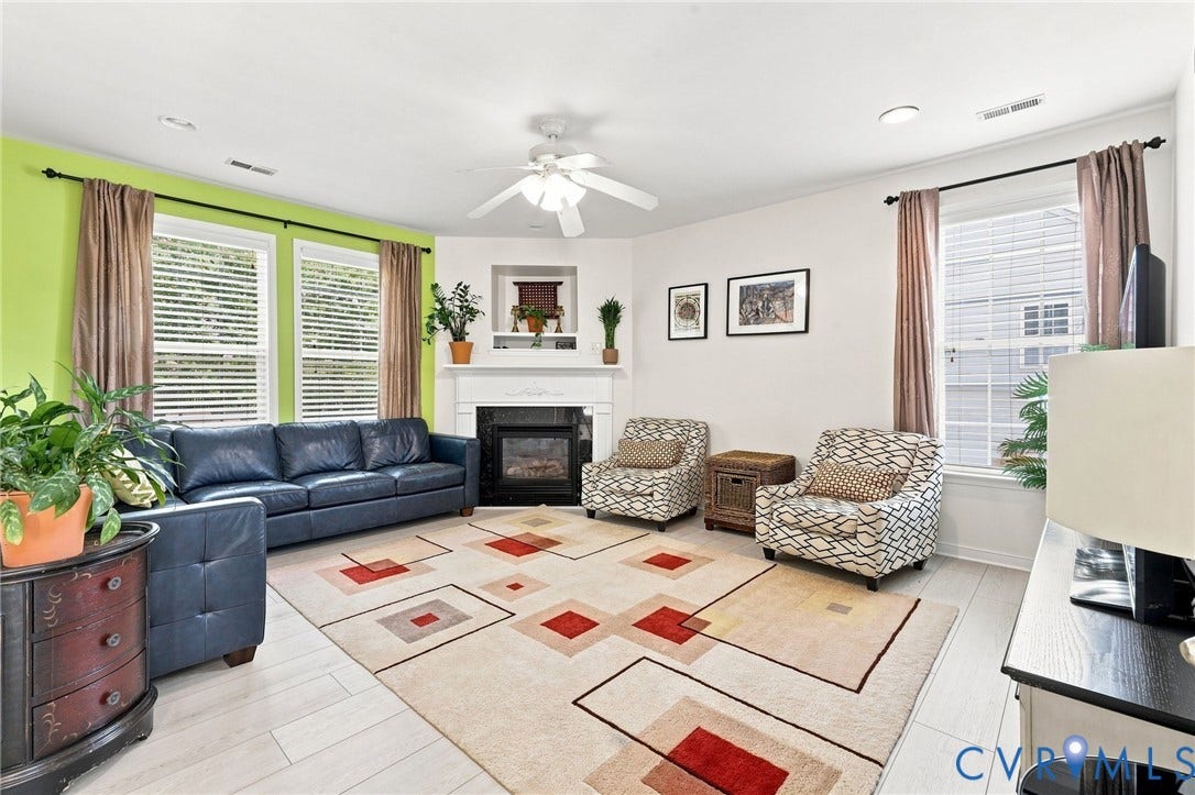 Living area featuring light wood-finish flooring, a white mantel, and a built-in fireplace