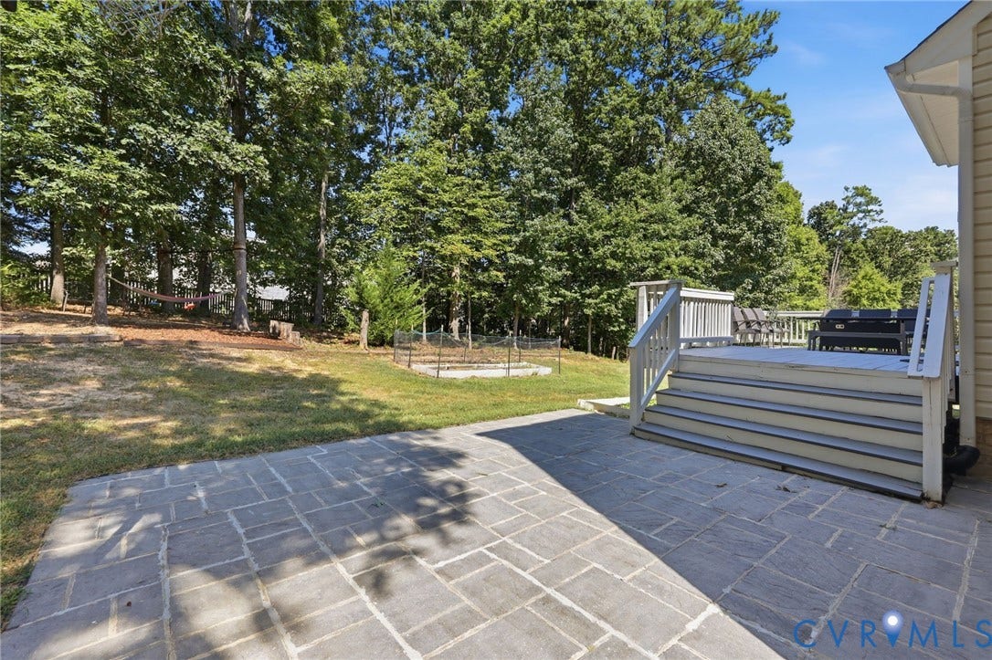 Spacious backyard featuring a paver patio, multi-level deck with railings, and mature trees