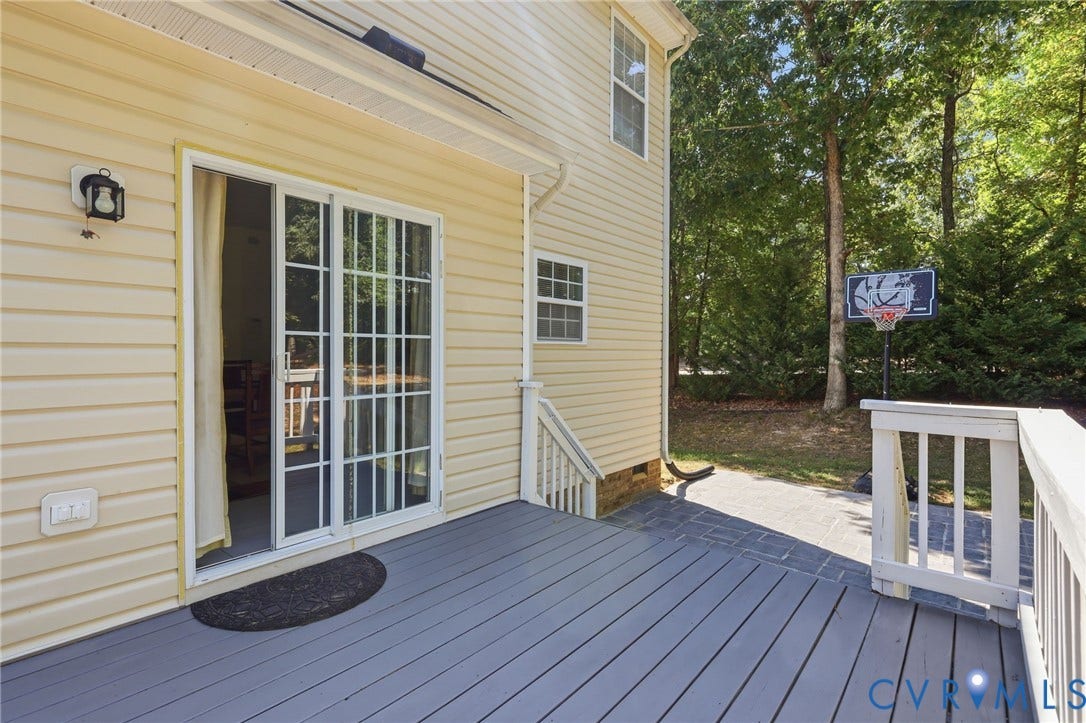 Spacious rear deck with painted wood planks, white railing, and sliding glass door access