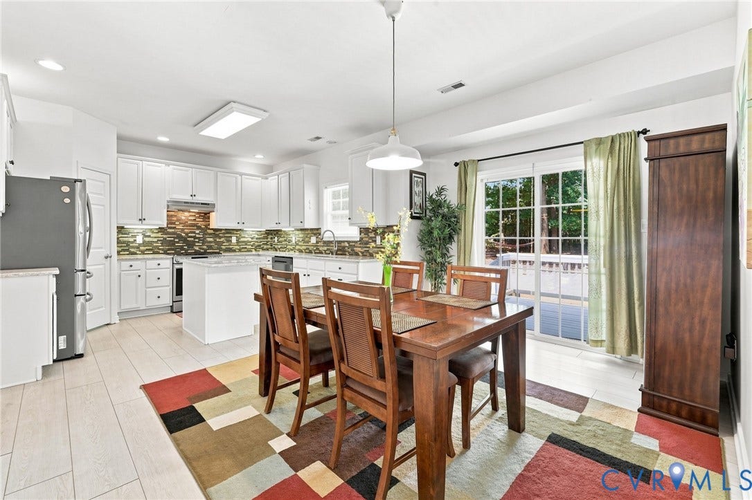 Kitchen featuring white cabinetry, a central island, stainless steel appliances, and a mosaic tile backsplash