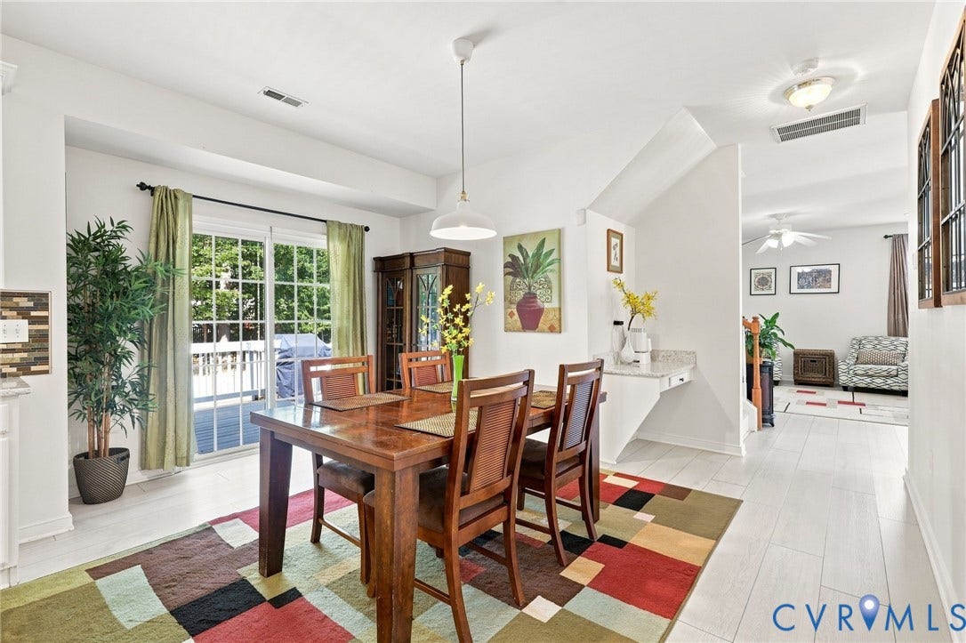 Spacious dining area with light-toned flooring, featuring a sliding glass door for exterior access