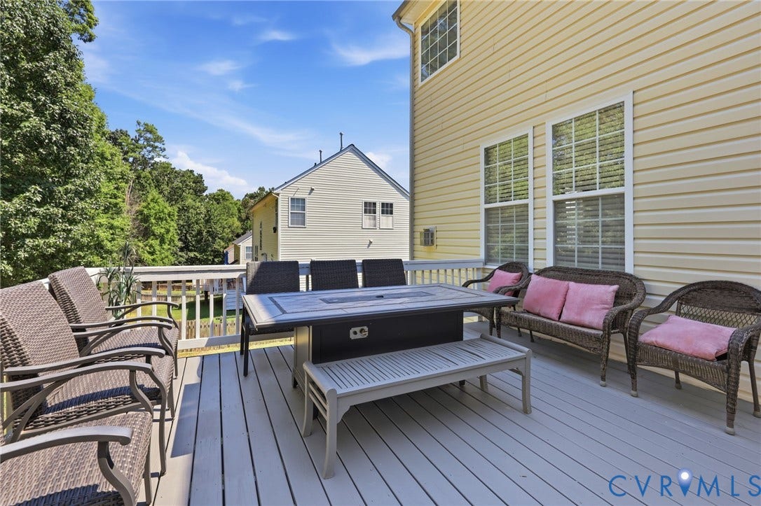 Expansive wood-finish deck with white railings, featuring vinyl siding and multiple windows