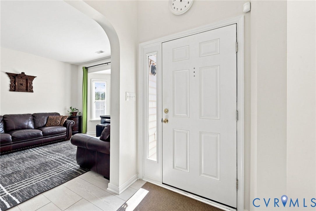 Entryway with a paneled door, sidelight, and light-toned tile flooring