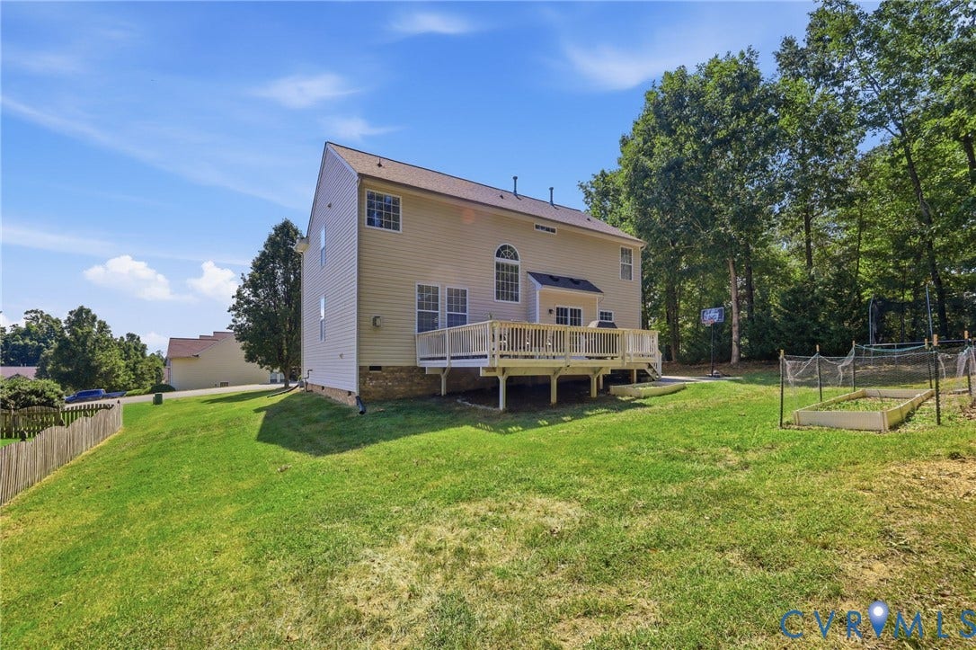 Expansive backyard featuring a wood deck, established garden beds, and mature trees