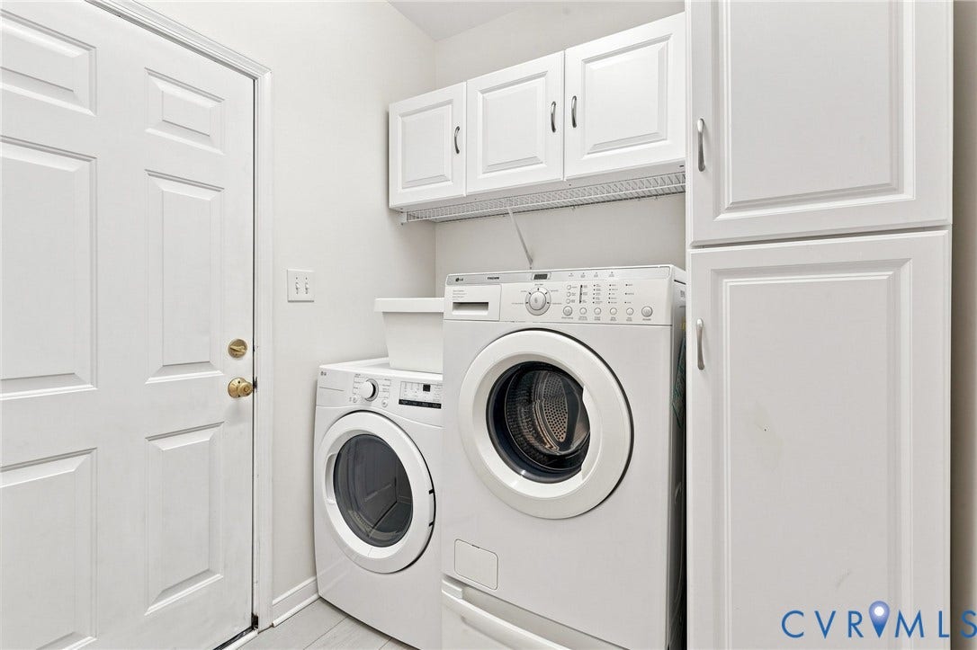 White paneled door with brass hardware, upper wall cabinetry, floor-to-ceiling storage cabinetry, and tiled flooring