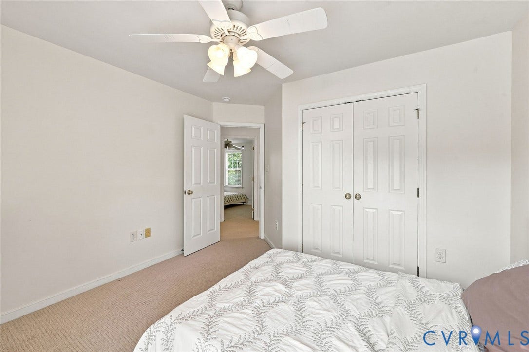 Neutral wall paint, carpet flooring, ceiling fan with integrated lighting, and white paneled doors