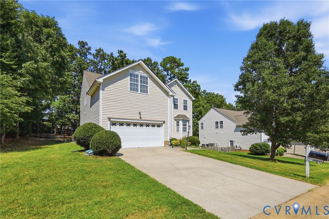 Two-story residence with light-toned siding, attached garage, and a concrete driveway