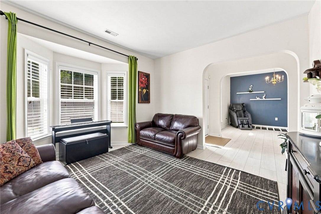 Bay window with white blinds, arched doorway, and light-toned tile flooring