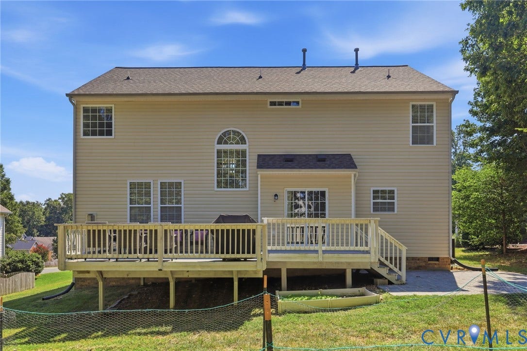 Rear exterior with neutral-toned siding, multi-level wood deck, and a sliding glass door
