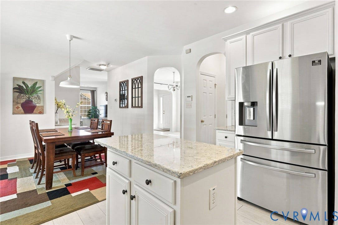 Kitchen featuring a stainless steel French door refrigerator, white cabinetry, a kitchen island with a light-toned countertop, and recessed lighting