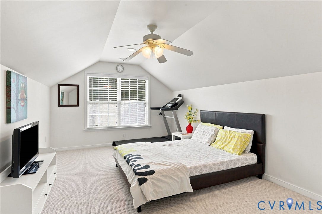 Vaulted ceiling with ceiling fan, white paneled window with blinds, carpeted flooring