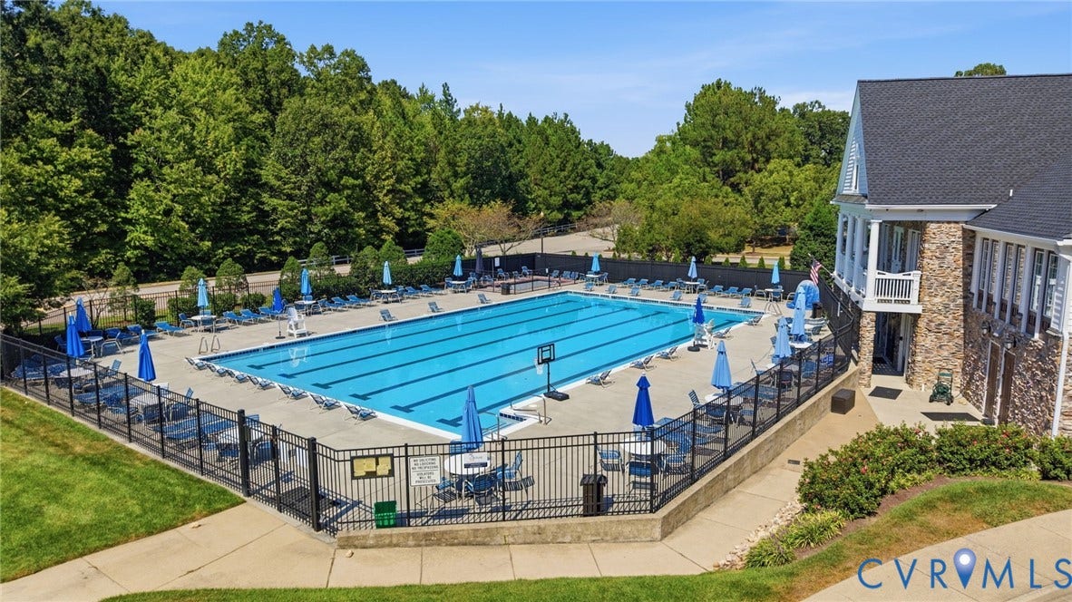 Community pool with multiple swimming lanes, expansive concrete surround, and perimeter fencing