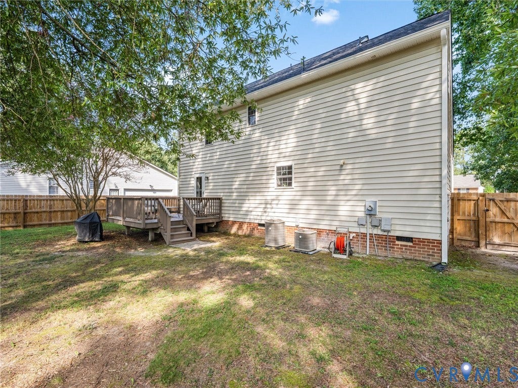 Private backyard featuring a wood deck with stairs, wood fencing, and mature trees