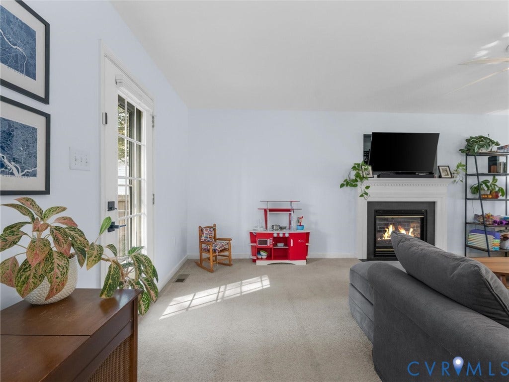 Light-toned wall paint, neutral carpeting, and a fireplace with a white mantel