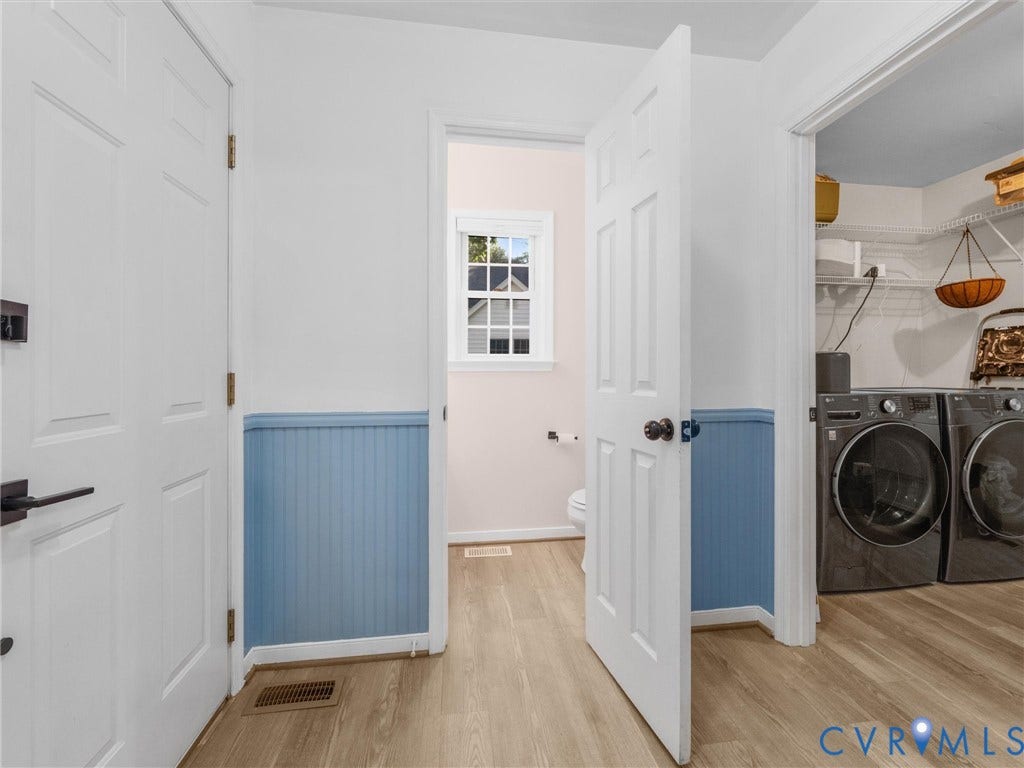 Laundry area featuring a side-by-side washer and dryer, wire shelving, and wood-finish flooring