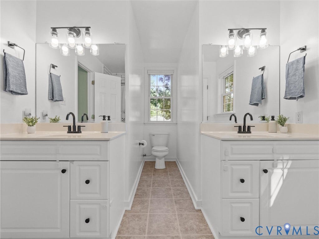 Dual vanity with white cabinetry, light countertops, matte black fixtures, and framed mirrors