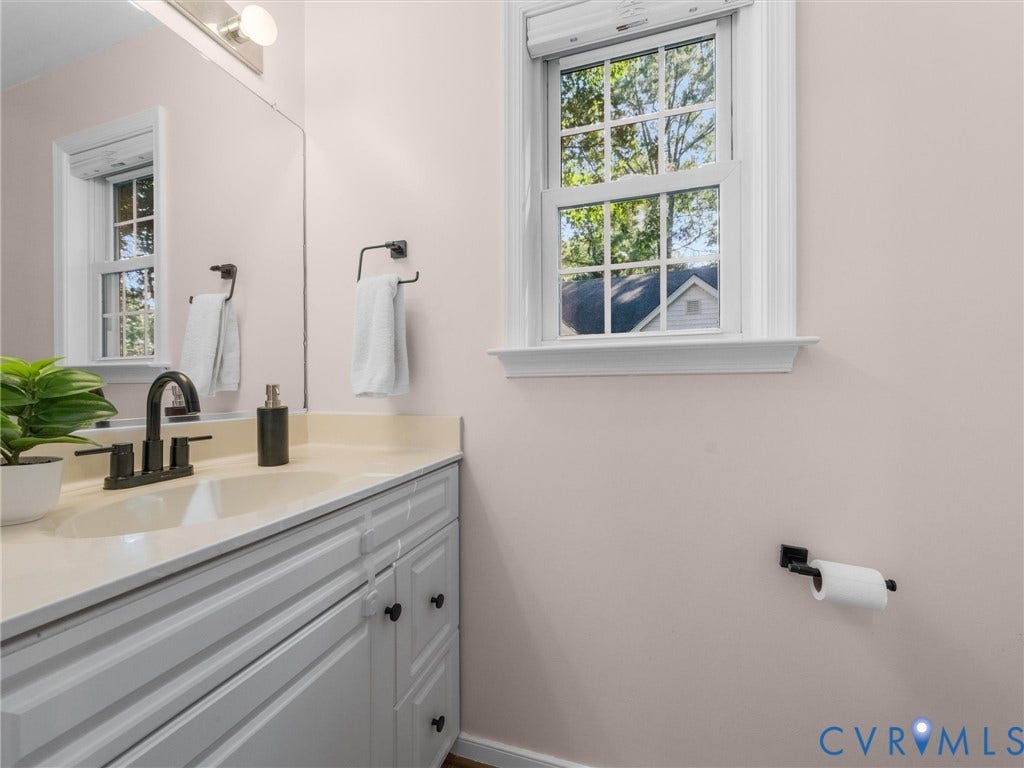 White vanity with fluted cabinet doors, light-toned countertop, and integrated sink