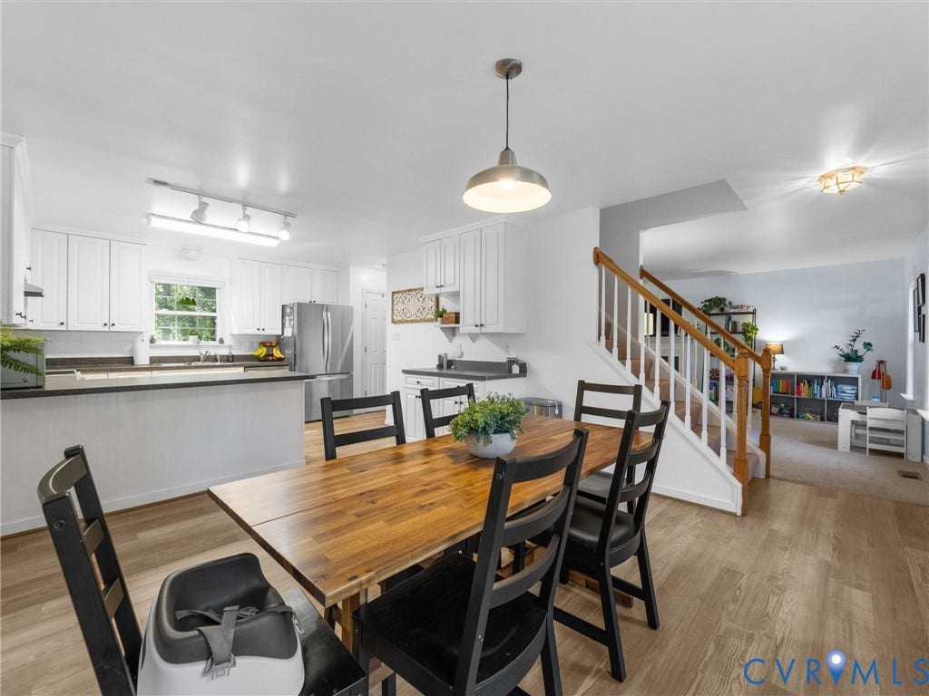 Kitchen with white cabinetry, dark countertops, stainless steel refrigerator, and wood-finish flooring
