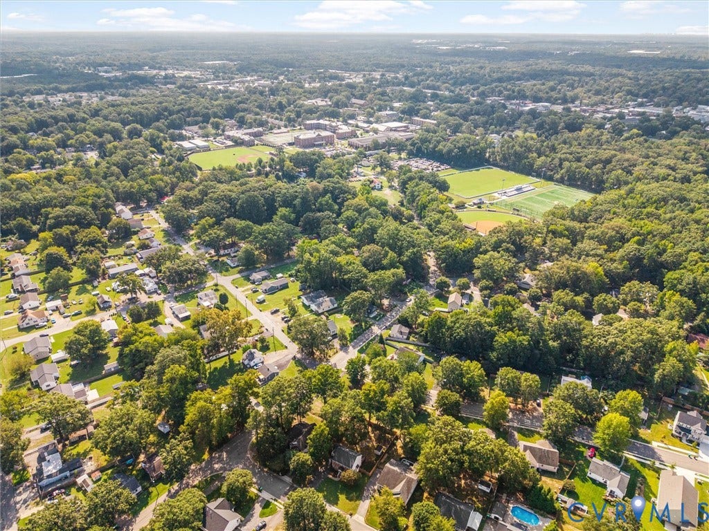 Aerial perspective showcasing a residential area with extensive tree coverage and open green spaces