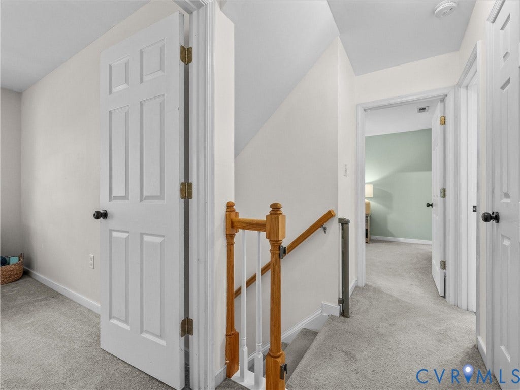 Carpeted hallway with painted walls and multiple paneled doors