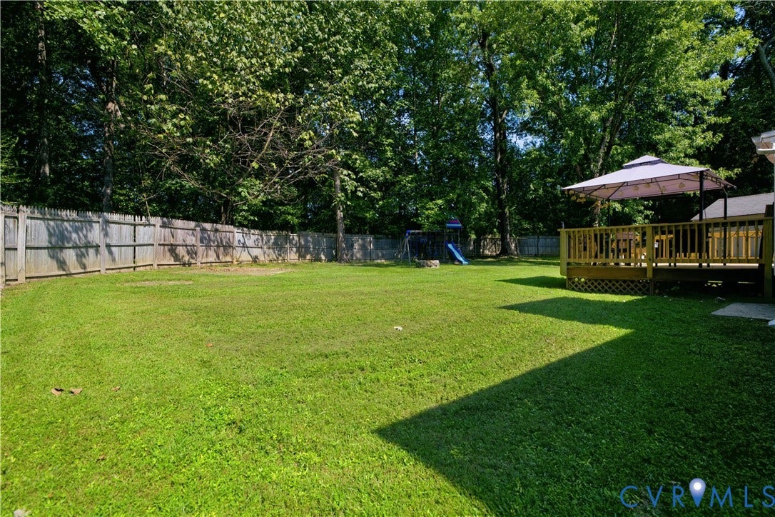 13602 Velvet Antler Place, Midlothian, VA 23112 Expansive fenced backyard featuring a manicured lawn, mature trees, and a spacious wood deck
